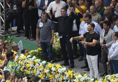 El presidente brasileño Jair Bolsonaro levanta los brazos para saludar a sus simpatizantes durante un evento de campaña en Duque de Caxias, en el estado de Río de Janeiro, Brasil, el viernes 14 de octubre de 2022. (AP Foto/Silvia Izquierdo)