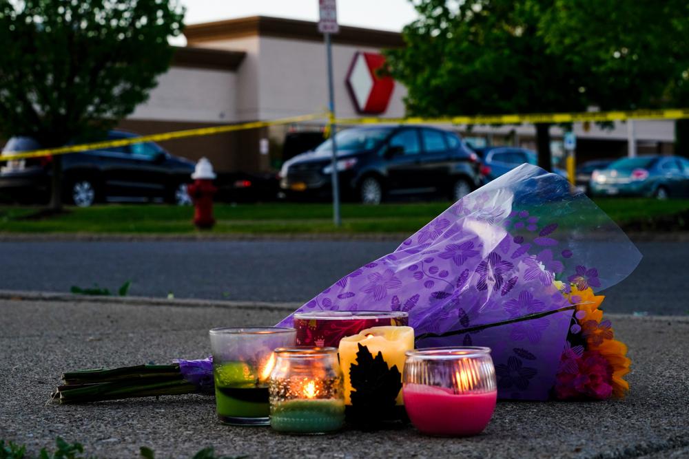 Flowers and candles lay outside the scene of a shooting at a supermarket, in Buffalo, N.Y., Sunday, May 15, 2022. (AP Photo/Matt Rourke)