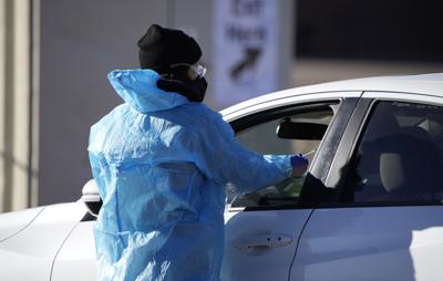 FILE - A medical technician performs a nasal swab test on a motorist queued up in a line at a COVID-19 testing site near All City Stadium Dec. 30, 2021, in southeast Denver. Millions of workers whose jobs don't provide paid sick days are having to choose between their health and their paycheck as the omicron variant of COVID-19 rages across the nation. While many companies instituted more robust sick leave policies at the beginning of the pandemic, those have since been scaled back with the rollout of the vaccines, even though the omicron variant has managed to evade them. (AP Photo/David Zalubowski, File)