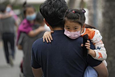 Varias personas llevan a sus niños a un kínder, con mascarillas para protegerse del coronavirus, el 9 de junio del 2021, en Beijing. (AP Foto/Andy Wong)