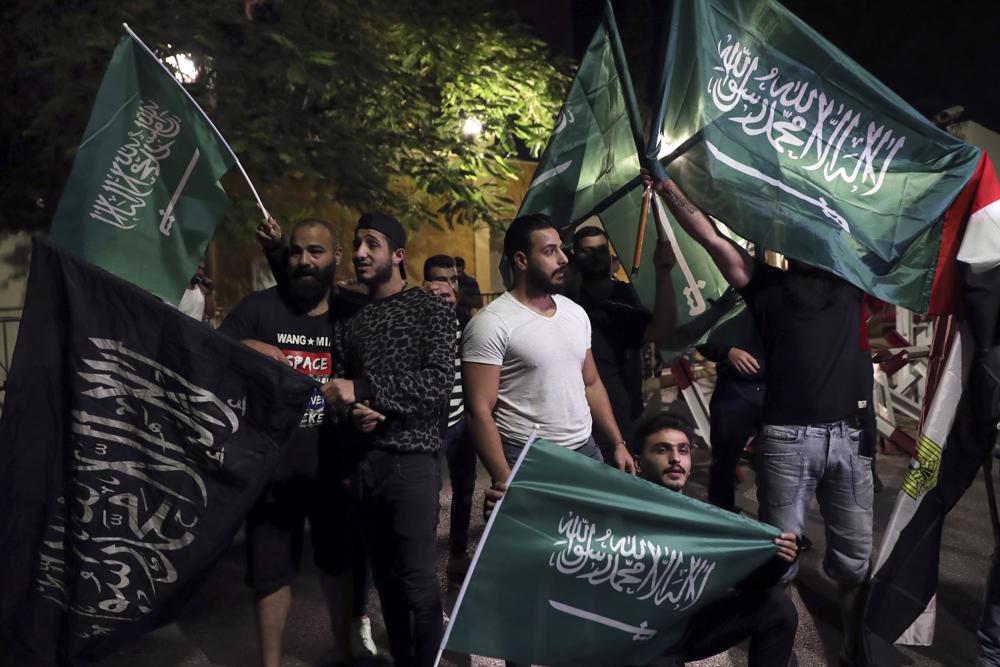 FILE - Lebanese hold Saudi Arabian flags during a rally in support of the kingdom against comments made by Lebanon's Information Minister George Kordahi over the war in Yemen, in front of the Saudi Arabia Embassy in Beirut, Lebanon, Oct. 30, 2021. Job opportunities lost and contracts canceled are just some of the ways that ordinary Lebanese have been affected by Saudi Arabia’s furious backlash at Lebanon late last month. Saudi Arabia recalled its ambassador and banned Lebanese imports ranging from chocolate to chemical products, which used to bring in about $240 million a year. (AP Photo/Bilal Hussein, File)