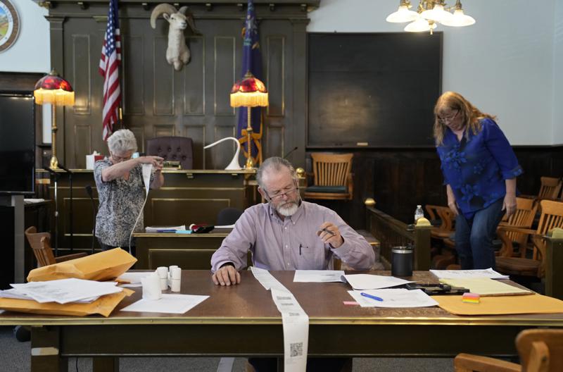 ARCHIVO - El comisionado del condado de Esmeralda, Ralph Keyes, centro, trabaja en un recuento manual de votos con otros, el 24 de junio de 2022, en Goldfield, Nevada. Una encuesta de AP muestra que la mayoría de los candidatos que se postulan este año para los puestos estatales que supervisan las elecciones se oponen a la idea de contar las boletas a mano, un proceso laborioso y propenso a errores que ha ganado el favor de los republicanos que han sido inundados con teorías de conspiración infundadas sobre máquinas de votación. (AP Photo/John Locher, Archivo)