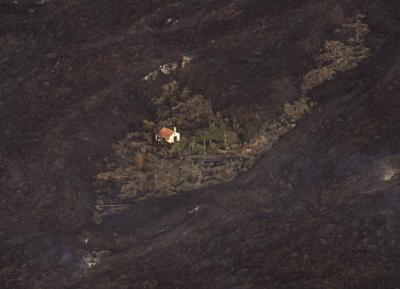 Lava procedente de una erupción volcánica rodean una casa en la isla de La Palma, en Islas Canarias, España, el 23 de septiembre de 2021. (AP Foto/Emilio Morenatti, Pool)