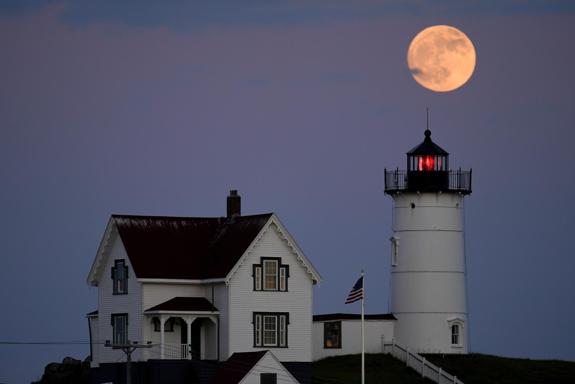 A waxing gibbous moon is seen at 98% percent full as it rises near the Nubble Light, Monday, June 13, 2022, in York, Maine. The moon will reach its full stage on Tuesday, during a phenomenon known as a Supermoon because its proximity to Earth, and it is also labeled as the "Strawberry Moon" because it is the full moon at strawberry harvest time. (AP Photo/Julio Cortez)