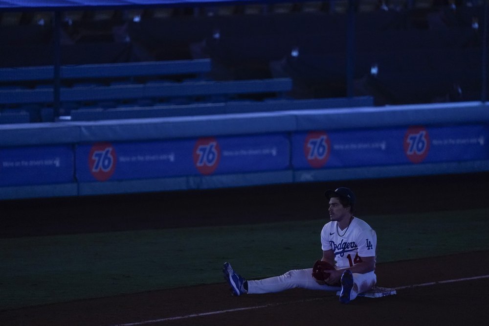 El jardinero izquierdo de los Dodgers de Los Ángeles Enrique Hernández se sienta en la tercera base durante un apagón que detuvo un juego de béisbol contra los Angelinos de Los Ángeles en la séptima entrada el sábado 26 de septiembre de 2020.