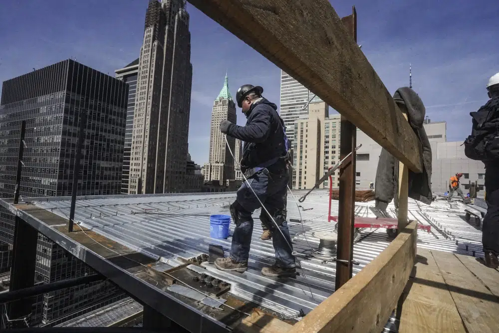 Archivo: los trabajadores de la construcción instalan un techo en un edificio alto en el distrito financiero de Manhattan el martes 11 de abril de 2023 en Nueva York.  El viernes, el gobierno de EE. UU. emite el informe de empleo de abril.  (Foto AP/Bebeto Matthews, archivo)