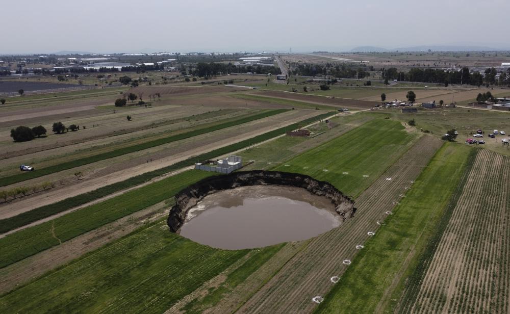 A water-filled sinkhole grows on a farming field in Zacatapec, on the outskirts of Puebla, Mexico, Tuesday, June 1, 2021. Authorities say an underground river is responsible. (AP Photo/Pablo Spencer)