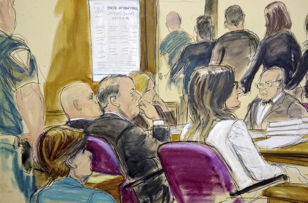 In this courtroom drawing, Harvey Weinstein, center, sits at the defense table surrounded by his attorneys as jurors file out of the courtroom after being told by the judge to go back and keep deliberating in Weinstein's rape case, Friday, Feb. 21, 2020, at Manhattan Supreme Court in New York. Earlier they sent out a note saying they were deadlocked on two charges. Attorney Gloria Allred, foreground left, is seated in the gallery behind Weinstein. (Elizabeth Williams via AP)