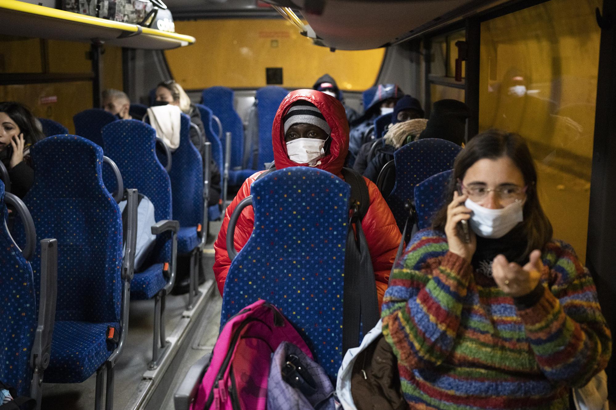 A migrant from Guinea headed to France sits on a bus to the Italian border town of Cesana to start a border crossing attempt though the French-Italian alps, Saturday, Dec. 11, 2021. (AP Photo/Daniel Cole)