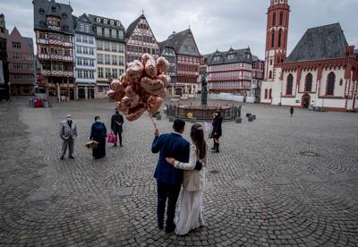 Fotografía de archivo del 5 de marzo de 2021, de una pareja posando en la plaza Roemerberg después de casarse en Fráncfort, Alemania, cuando debido a la pandemia de coronavirus estaban prohibidas las fiestas de boda. (AP Foto/Michael Probst)