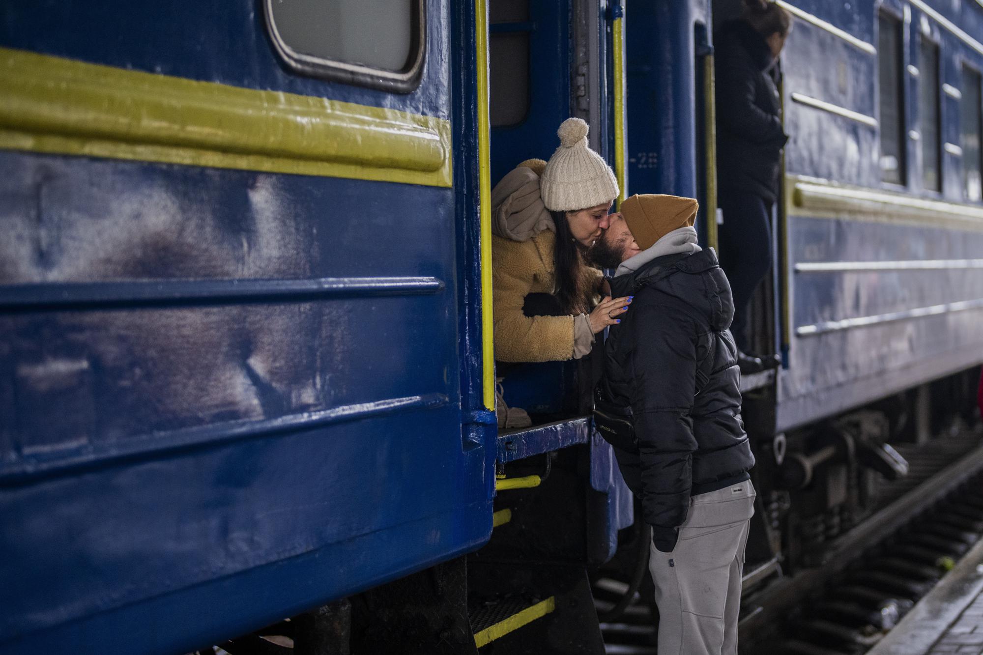 Stanislav, 40, kisses his wife Anna, 35, on a train to Lviv as they say goodbye at the Kyiv station, Ukraine, Thursday, March 3. 2022. Stanislav is staying to fight while his family is leaving the country to seek refuge in a neighboring country. (AP Photo/Emilio Morenatti)