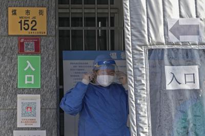 Un trabajador con traje protector ajusta su mascarilla mientras se prepara para laborar en un sitio de vacunación COVID-19 cerca de la calle Qianmen, en Beijing, el miércoles 17 de noviembre de 2021 (Foto AP / Andy Wong).