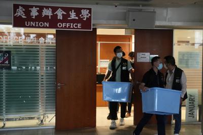 Policías sacan cajas con documentos de las oficinas de un sindicato estudiantil en la Univrsidad de Hong Kong el 16 de julio del 2021. La policía de seguridad de Hong Kong allanó el sitio luego que líderes estudiantiles conmemoraron la semana pasada a un hombre que se suicidó tras acuchillar a un policía.  (AP Foto/Kin Cheung)