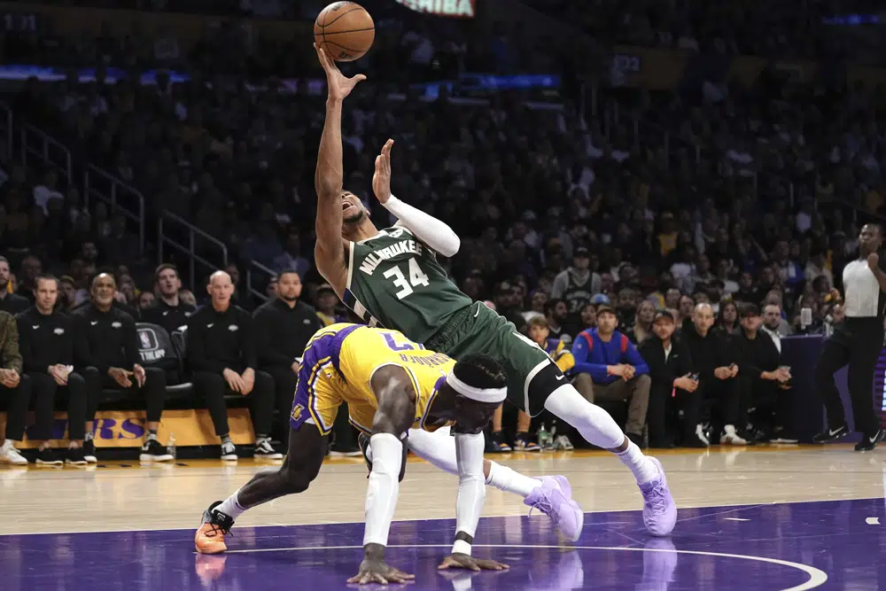 密尔沃基雄鹿队前锋吉安尼斯·阿德托昆博（右）在 9 年 2023 月 <> 日星期四在洛杉矶举行的一场 NBA 篮球比赛的上半场防守时投篮，洛杉矶湖人队后卫丹尼斯·施罗德防守。（美联社照片/Mark J. Terrill）