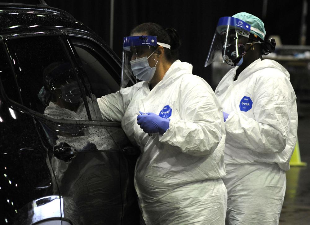 FILE - In this Aug. 12, 2021 file photo, workers from USA Health test a person for COVID-19 during a drive-up clinic in Mobile, Ala. Health officials say they are seeing a spike in cases among young adults and children  as the highly contagious delta variant sweeps through unvaccinated populations.  (AP Photo/Jay Reeves, File)