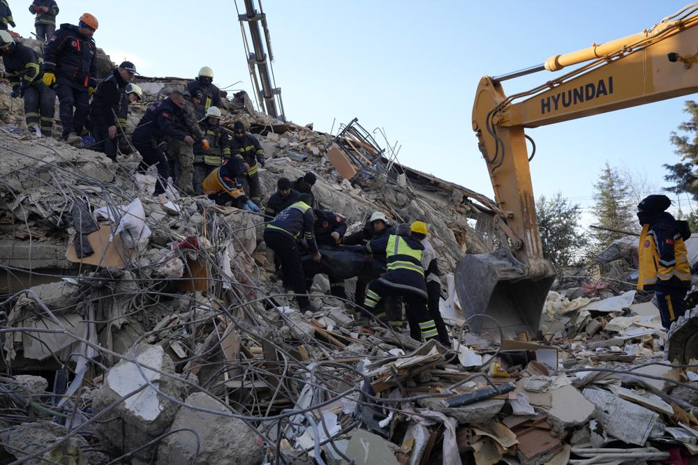 Firefighters carry a dead body from a destroyed building, in Gaziantep, southeastern Turkey, Wednesday, Feb. 8 , 2023. Thinly stretched rescue teams worked through the night into Wednesday, pulling more bodies from the rubble of thousands of buildings downed in Turkey and Syria by a catastrophic earthquake. (AP Photo/Kamran Jebreili)