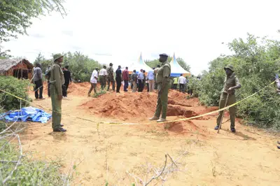 Agentes de la policía cerca de un cordón en el sitio donde la policía está exhumando los cuerpos de víctimas de una secta religiosa, en la localidad de Malindi, en Kenia, el martes 25 de abril de 2023. (AP Foto)