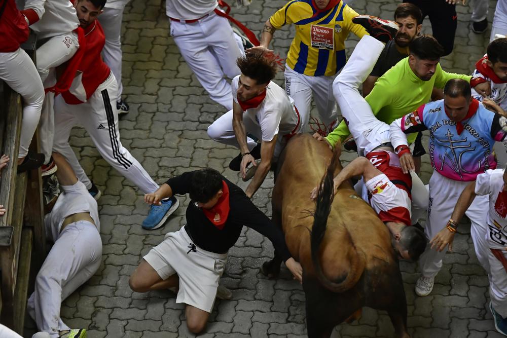 A fighting bull turns and charges runners during the running of the bulls at the San Fermin Festival in Pamplona, northern Spain, Monday, July 11, 2022. Revellers from around the world flock to Pamplona every year for nine days of uninterrupted partying in Pamplona's famed running of the bulls festival which was suspended for the past two years because of the coronavirus pandemic. (AP Photo/Alvaro Barrientos)