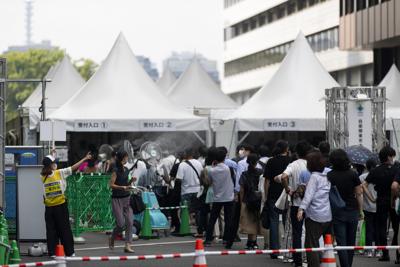 Una trabajadora (izquierda) dirige a la gente para que se registren para recibir la vacuna de Pfizer-BioNTech contra el COVID-19 en Tokio, el 26 de agosto de 2021. (AP Foto/Hiro Komae)