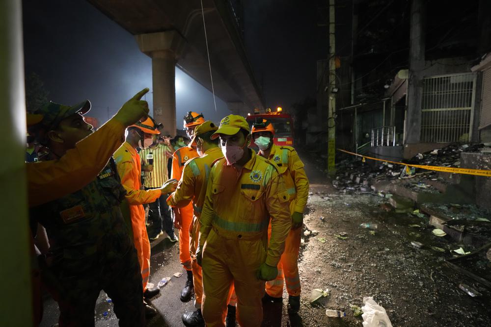 National Disaster Response Force soldiers help fire officials to douse a fire in a four storied building, in New Delhi, India, Saturday, May 14, 2022. A massive fire erupted in a four-storied building in the Indian capital on Friday, killing at least 19 people and leaving several injured, the fire control room said. Dozens of people have been rescued from the commercial building, mainly shops, in the Mundka area in the western part of New Delhi. (AP Photo/Manish Swarup)