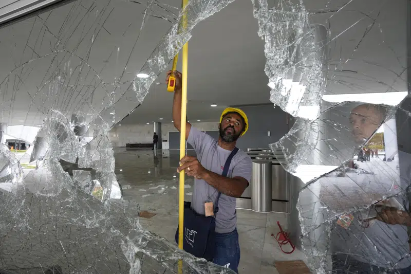 Workers measure the windows at Planalto Palace the day after it was stormed by supporters of Brazil's former President Jair Bolsonaro in Brasilia, Brazil, Monday, Jan. 9, 2023. The protesters also stormed Congress and the Supreme Court. (AP Photo/Eraldo Peres)