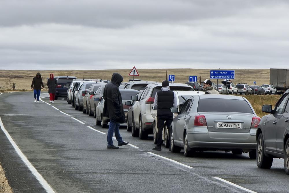 La gente camina junto a sus automóviles haciendo fila para cruzar la frontera con Kazajistán en el paso fronterizo de Mariinsky, a unos 400 kilómetros (250 millas) al sur de Chelyabinsk, Rusia, el martes 27 de septiembre de 2022. (AP Foto)