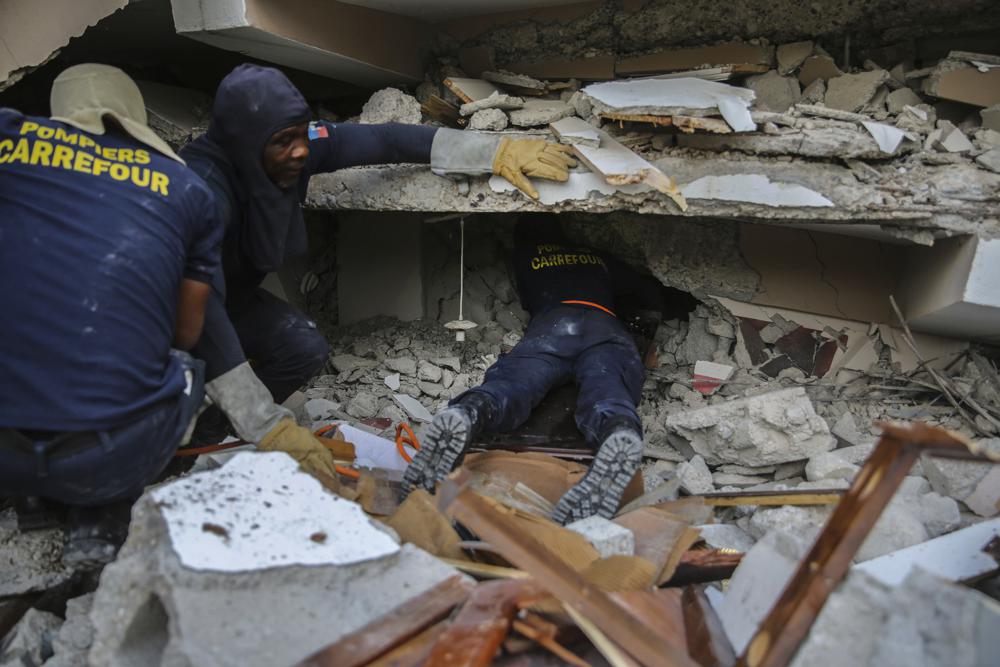 Firefighters search for survivors inside a collapsed building, after Saturday´s 7.2 magnitude earthquake in Les Cayes, Haiti, Sunday, Aug. 15, 2021. (AP Photo/Joseph Odelyn)