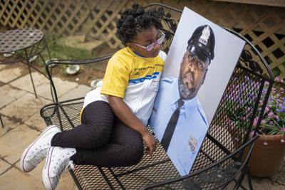 Amethyst, la hija de 5 años de Erin Tokley, un policía de Filadelfia que murió a causa del COVID-19 en marzo, posa junto a una fotografía de su padre el 29 de agosto de 2021, en Secane, Pensilvania. (AP Foto/Laurence Kesterson)