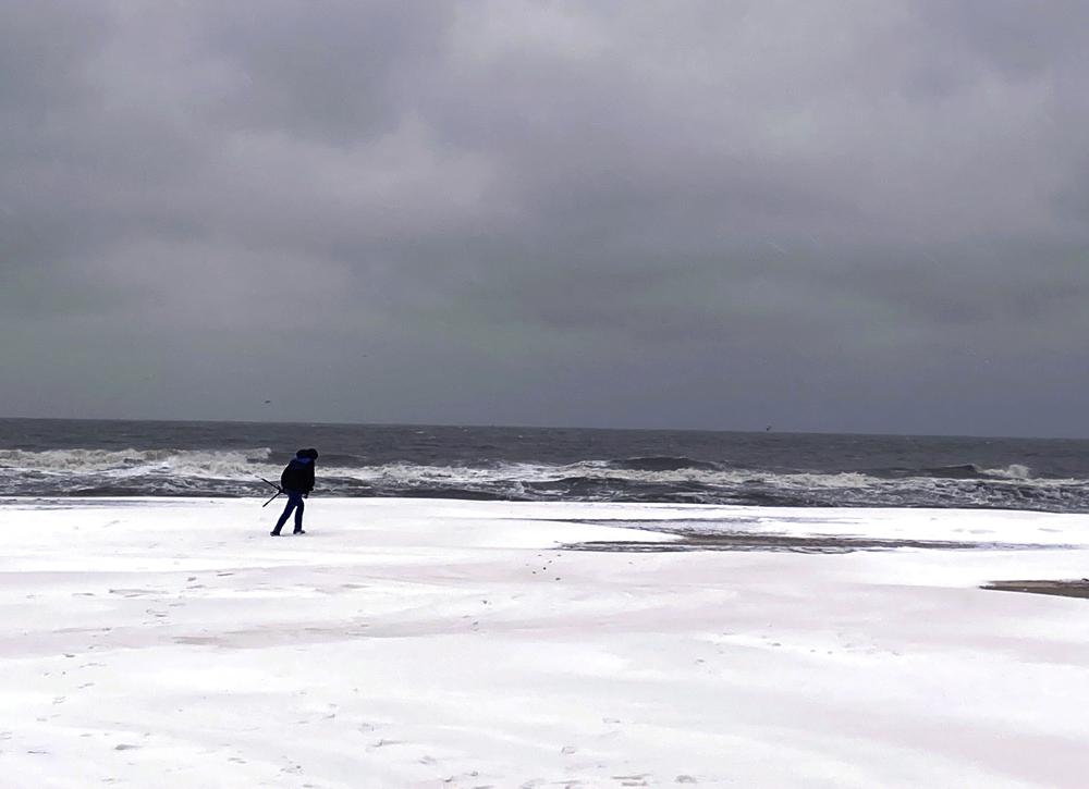 Una persona camina a lo largo de la costa de Virginia Beach cubierta de nieve, el sábado 22 de enero de 2022. Una capa de hielo y un manto de nieve han cubierto las áreas costeras que se extienden desde Carolina del Sur hasta Virginia.  El sistema de clima invernal que ingresó a la región el viernes trajo temperaturas más frías y precipitaciones que no se ven con frecuencia en la región.  (Stacy Parker/The Virginian-Pilot vía AP)