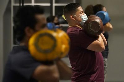 Juan Avellan, centro, y otras personas usan mascarillas al interior de una clase en el gimnasio Hit Fit SF durante el brote de coronavirus en San Francisco, el martes 24 de noviembre de 2020. (AP Foto/Jeff Chiu)