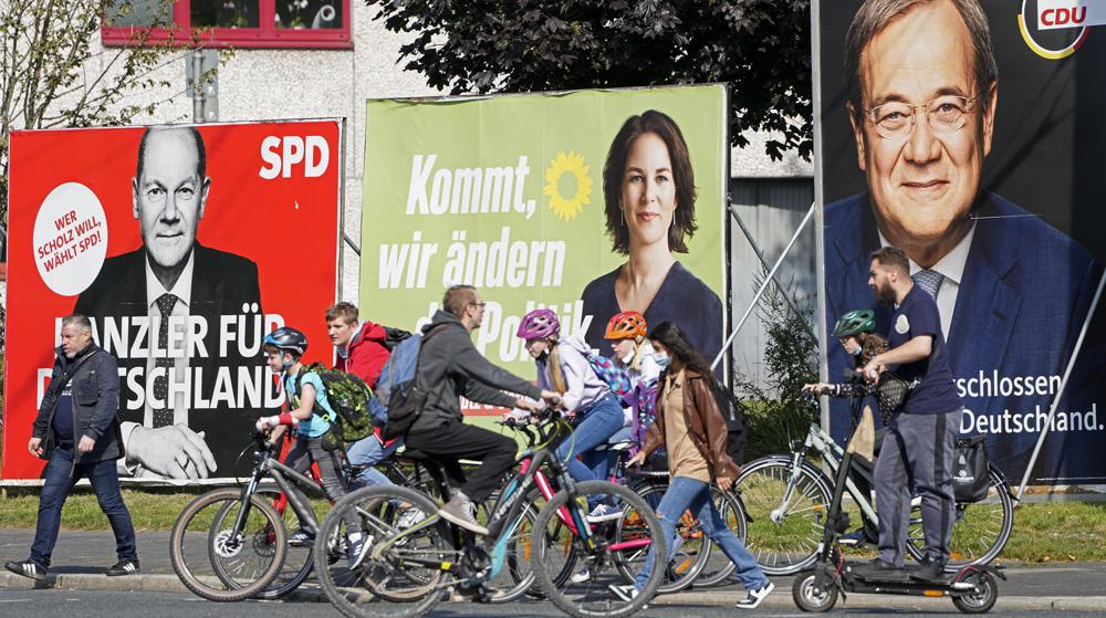 FILE - In this Thursday, Sept. 23, 2021 file photo, People walk and drive past election posters of the three candidates for German chancellor , from right, Armin Laschet, Christian Democratic Union (CDU), Annalena Baerbock, German Green party (Die Gruenen) and Olaf Scholz, Social Democratic Party (SPD), at a street in Gelsenkirchen, Germany. Germany’s closely fought election on Sunday will set the direction of the European Union’s most populous country after 16 years under Angela Merkel, whose party is scrambling to avoid defeat by its center-left rivals after a rollercoaster campaign. (AP Photo/Martin Meissner, File)