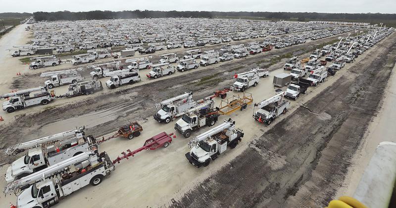Utility trucks are staged in a rural lot in The Villages of Sumter County, Fla., Wednesday, Sept. 28, 2022. Hurricane Ian rapidly intensified as it neared landfall along Florida's southwest coast Wednesday morning, gaining top winds of 155 mph (250 kph), just shy of the most dangerous Category 5 status.  (Stephen M. Dowell/Orlando Sentinel via AP)