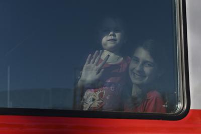 Una mujer y su hija, de las regiones de Donetsk y Luhansk _territorios controlados por gobiernos separatistas prorrusos en el este de Ucrania_, saludan desde un tren en camino a un albergue temporal en otra región de Rusia, el lunes 21 de febrero de 2022, en la estación ferroviaria de Taganrog, Rusia. (AP Foto)