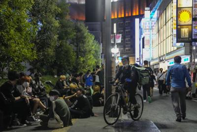 Personas reunidas frente a un bar de Tokio que sigue vendiendo bebidas alcohólicas después de las ocho de la noche, a pesar de que las autoridades pidieron que dejasen de hacerlo para combatir la propagación del coronavirus durante los Juegos Olímpicos. Foto del 17 de julio del 2021. (AP Photo/Kiichiro Sato)