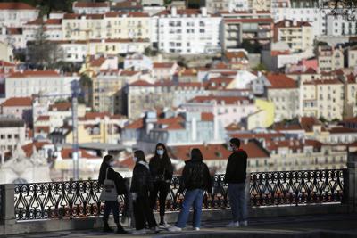 ARCHIVO -  En esta foto de archivo del 11 de marzo de 2021, jóvenes con mascarillas conversan en un mirador sobre el centro histórico de Lisboa. En los próximos fines de semana estará prohibido entrar o salir de la zona metropolitana de Lisboa debido a un pico de contagios de COVID-19, informaron las autoridades el jueves 17 de junio de 2021. (AP Foto/Armando Franca)