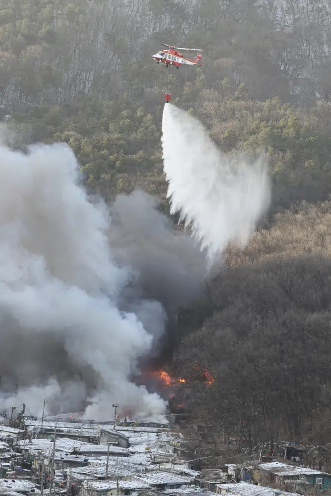 A National Fire Agency helicopter dumps water on a fire at Guryong village in Seoul, South Korea, Friday, Jan. 20, 2023. About 500 South Koreans were forced to flee their homes after a fire spread through a low-income neighborhood in southern Seoul on Friday morning and destroyed dozens of homes. (Kim Ju-sung/Yonhap via AP)