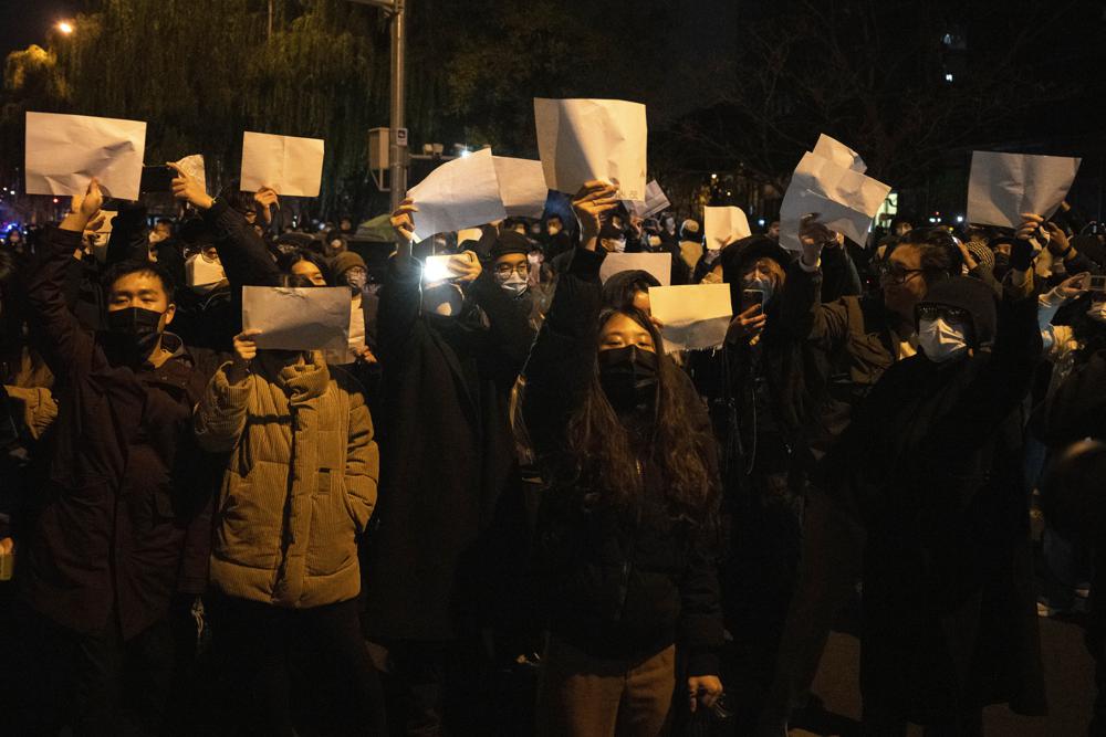 Protesters hold up blank papers and chant slogans as they march in protest in Beijing, Sunday, Nov. 27, 2022. Protesters angered by strict anti-virus measures called for China's powerful leader to resign, an unprecedented rebuke as authorities in at least eight cities struggled to suppress demonstrations Sunday that represent a rare direct challenge to the ruling Communist Party. (AP Photo/Ng Han Guan)