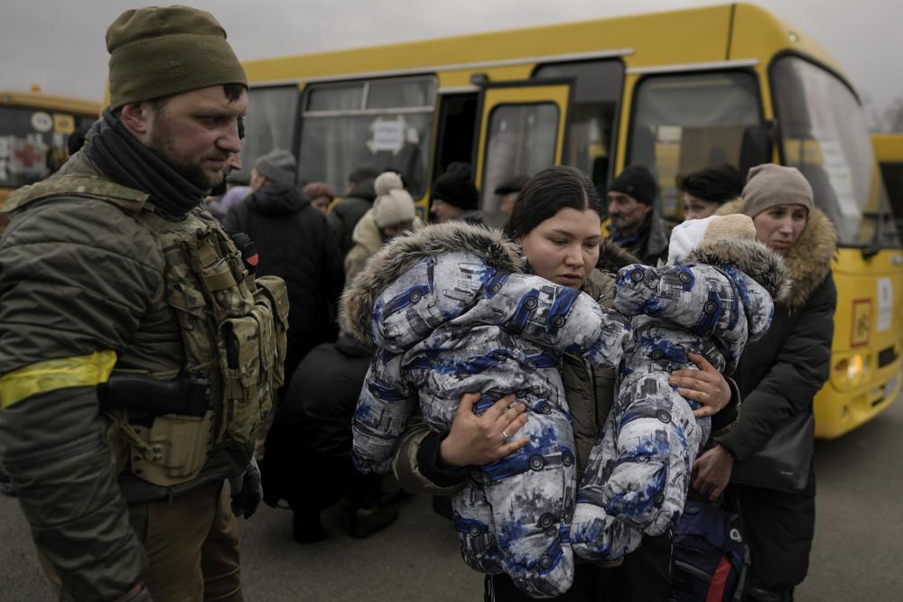 A woman who was evacuated areas around the Ukrainian capital, carries two babies after arriving at a triage point in Kyiv, Ukraine, Wednesday, March 9, 2022. A Russian airstrike devastated a maternity hospital Wednesday in the besieged port city of Mariupol amid growing warnings from the West that Moscow's invasion is about to take a more brutal and indiscriminate turn. (AP Photo/Vadim Ghirda)