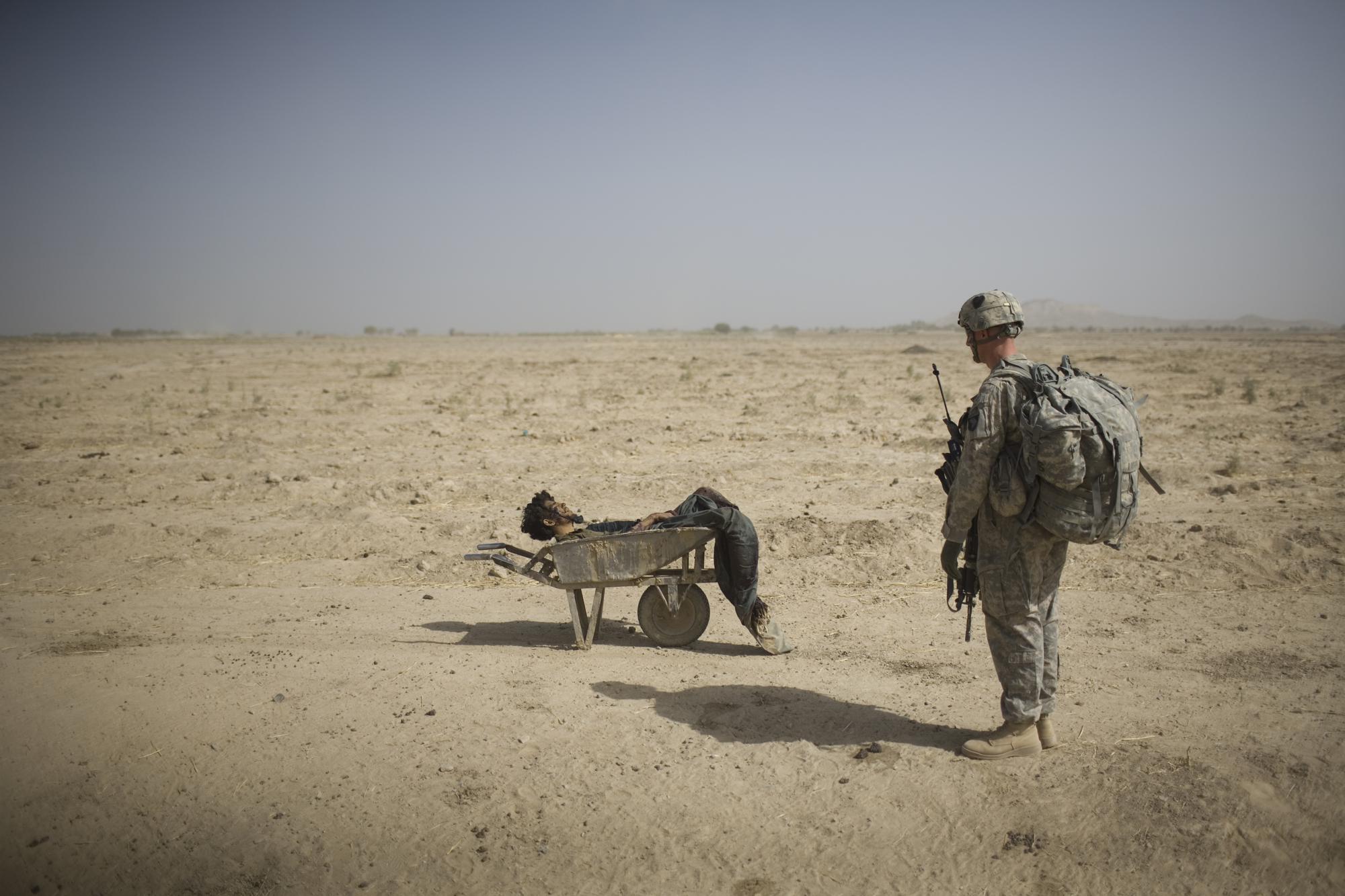 A U.S. Army soldier from Scout Platoon 502 Infantry Regiment, 101st Airborne Division, looks at the body of a suspected Taliban IED emplacer who was killed in a coalition missile strike in Zhari district, Kandahar province, Sunday, Oct. 10, 2010. The Scouts' mission was to support roadside bomb clearance efforts in the militant stronghold, the latest days-long phase of Operation Dragon Strike. (AP Photo/Rodrigo Abd)
