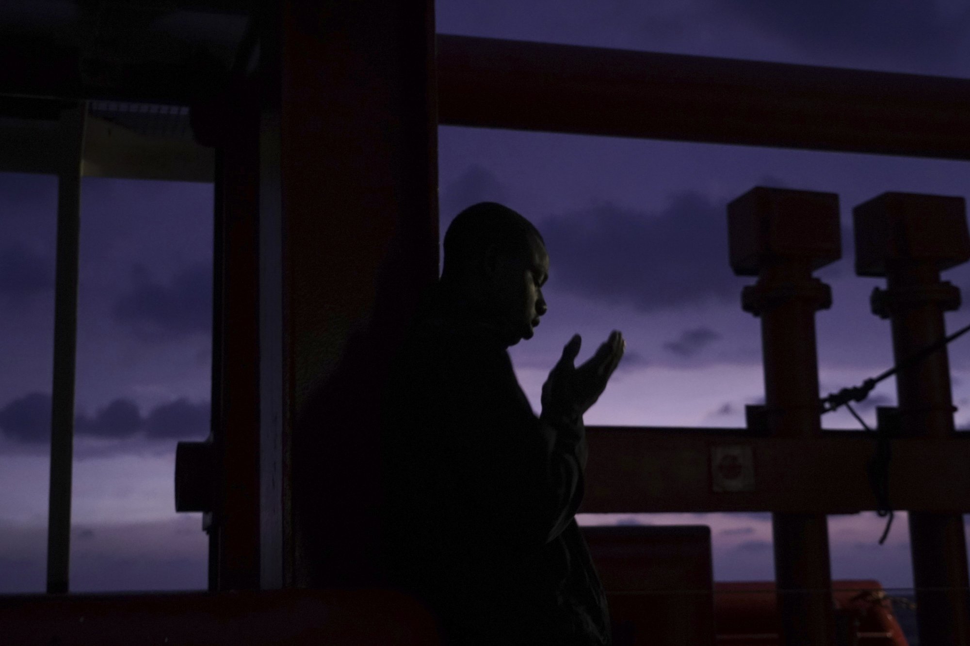 In this Sept. 22, 2019 photo, a rescued migrant prays aboard the Ocean Viking humanitarian ship in the Mediterranean Sea. The misery of migrants in Libya has spawned a thriving and highly lucrative business, in part funded by the EU and enabled by the United Nations, an Associated Press investigation has found. (AP Photo/Renata Brito)