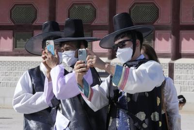 Un grupo de hombres, con mascarilla para protegerse del coronavirus, toman fotografías durante una visita al Palacio de Gyeongbok para celebrar el Chuseok, la versión coreana del Día de Acción de Gracias, en Seúl, Corea del Sur, el 22 de septiembre de 2021. (AP Foto/Ahn Young-joon)