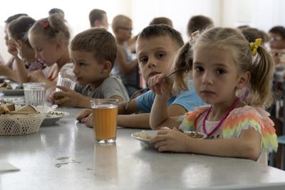 Niños de orfanatos de la región de Donetsk fotografiados durante el almuerzo en un campamento de Zolotaya Kosa, sobre el mar de Azov, el 8 de julio del 2022. Rusia se está apropiando de numerosos niños huéfanos ucranianos y se los está llevando a Rusia, según una investigación de la Associated Press. (AP Photo)