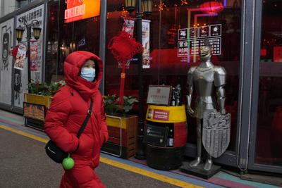Una mujer camina frente a una armadura frente a un restaurante en Beijing, China, el viernes 21 de enero de 2022. Paradójicamente, las amplias políticas de "tolerancia cero" que China ha empleado para proteger a su gente y economía del COVID-19 pueden hacer más difícil que el país salga de la pandemia. (AP Foto/Ng Han Guan)