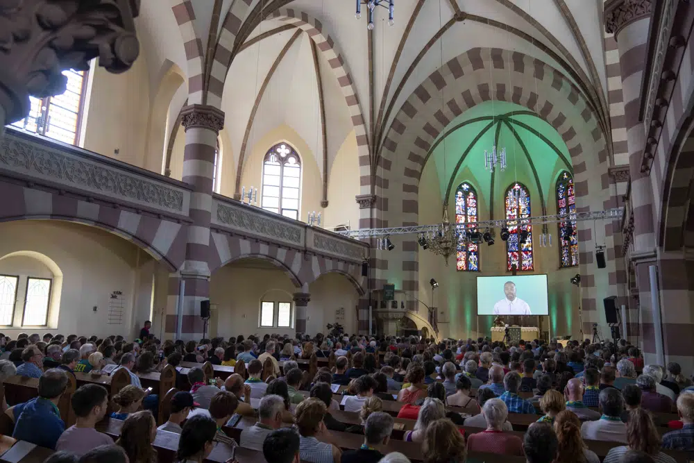 People attend a church service in Nuremberg, Germany, Friday, June 9, 2023. Hundreds of German Protestants have attended a church service in Bavaria that was generated almost entirely by artificial intelligence. The service was created by ChatGPT and Jonas Simmerlein, a theologian and philosopher from the University of Vienna. The ChatGPT chatbot, personified by different avatars on a huge screen above the altar, led the more than 300 people through 40 minutes of prayer, music, sermons and blessings. (AP Photo/Matthias Schrader)