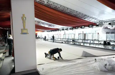 Un miembro del equipo grapa la alfombra blanca al suelo en preparación para la 95ª edición de los Premios de la Academia del domingo, el miércoles 8 de marzo de 2023, fuera del Teatro Dolby en Los Ángeles. (AP Photo/Chris Pizzello)