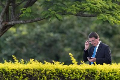 El presidente de Brasil, Jair Bolsonaro, mira su teléfono móvil mientras llega a una ceremonia de izamiento de bandera afuera del palacio de Alvorada, el jueves 17 de marzo de 2022, en Brasilia, Brasil. (AP Foto/Eraldo Peres)
