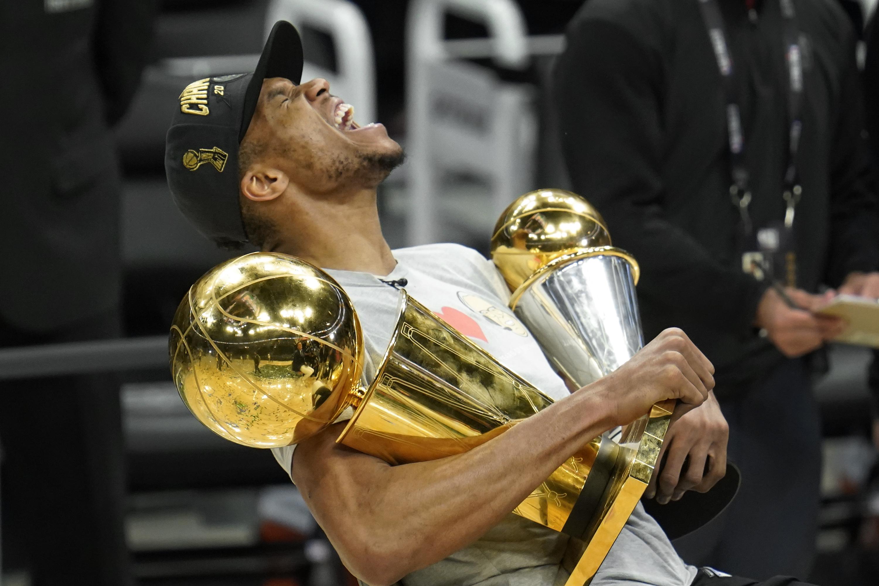 Antetokounmpo holds finals trophy and finals mvp trophy 