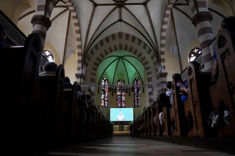 People attend a church service in Nuremberg, Germany, Friday, June 9, 2023. Hundreds of German Protestants have attended a church service in Bavaria that was generated almost entirely by artificial intelligence. The service was created by ChatGPT and Jonas Simmerlein, a theologian and philosopher from the University of Vienna. The ChatGPT chatbot, personified by different avatars on a huge screen above the altar, led the more than 300 people through 40 minutes of prayer, music, sermons and blessings. (AP Photo/Matthias Schrader)