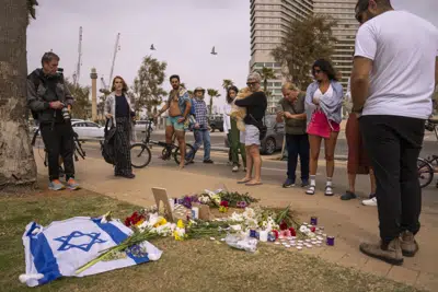 Un grupo de personas se congrega y coloca flores en el lugar donde murió el turista italiano Alessandro Parini en un ataque palestino, en Tel Aviv, Israel, el sábado 8 de abril de 2023. (AP Foto/Oded Balilty)
