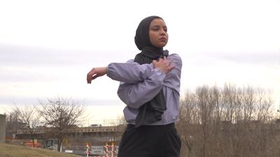 Esta imagen tomada del video muestra a Noor Abukaram estirando su brazo antes de correr por un sendero a lo largo del río Olentangy en la Universidad Estatal de Ohio el 2 de marzo de 2022. La mujer descalificada de una carrera de campo a través por usar un hijab está celebrando una nueva ley de Ohio que surgió de su experiencia. Noor Abukaram es un ex atleta de secundaria en los suburbios de Toledo y ahora es un estudiante de Ohio State. Abukaram es musulmán y fue descalificado de una carrera de secundaria en 2019 por usar un hijab. No había sido un problema hasta ese momento de la temporada. La ley defendida por la senadora estatal Theresa Gavarone prohíbe a los reguladores deportivos escolares exigir exenciones anticipadas o restringir la ropa religiosa de los participantes a menos que cause un "peligro legítimo". (AP Foto/Patrick Orsagos)